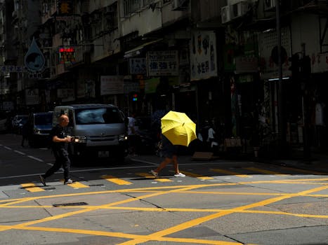 Colorful street scene in Hong Kong featuring people and a striking yellow umbrella.