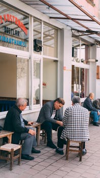 Group of men sitting and talking outside a Turkish café during the day.