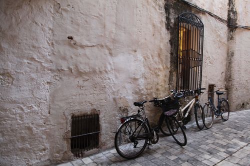 Free Bicycles leaning against a rustic wall in Ciudadela de Menorca, embodying Mediterranean charm. Stock Photo