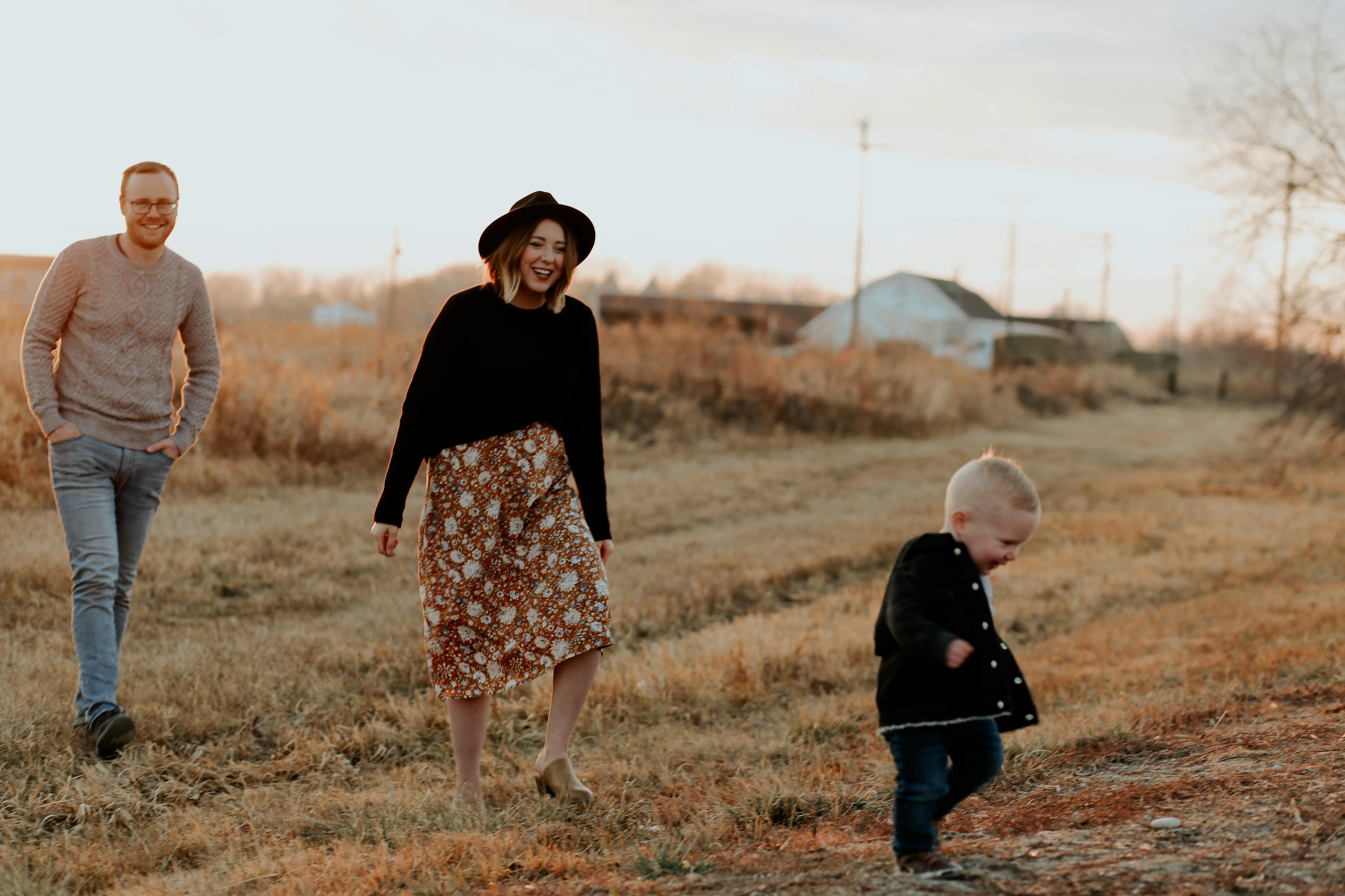 Couple and a Child Walking on Brown Grass