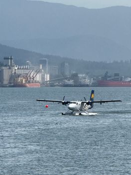 Captivating seaplane landing against Vancouver harbor's industrial backdrop.