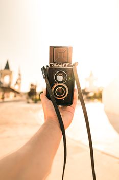 Hand holding a vintage camera on a sunny day in the city, capturing urban charm.
