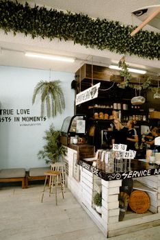 Chic coffee shop interior featuring modern design, greenery, and counter service.
