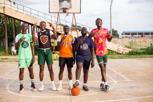 Free Five men posing on an outdoor basketball court with a basketball. Stock Photo