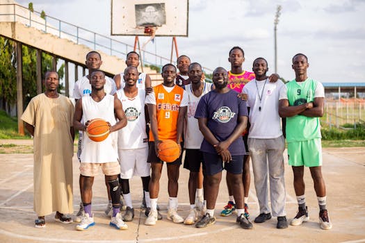 A cheerful group of basketball players posing on an outdoor court on a sunny day.