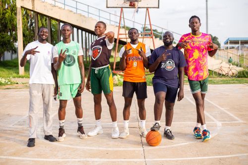 Free Group of young men posing on an outdoor basketball court, showing camaraderie. Stock Photo