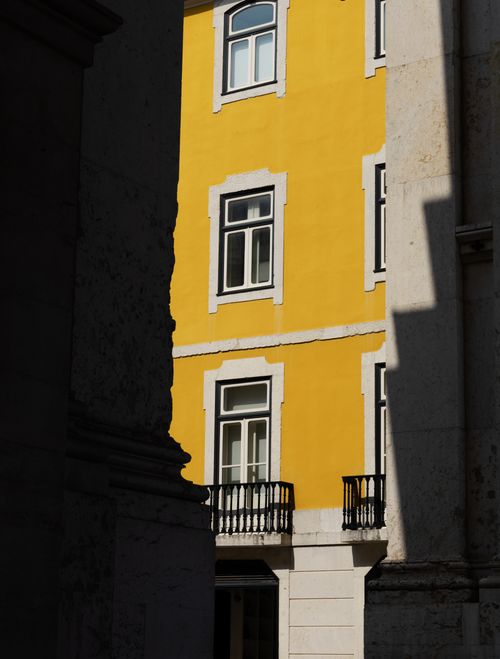 Free A vibrant yellow building facade lit by sunlight in Lisbon, Portugal's historic district. Stock Photo