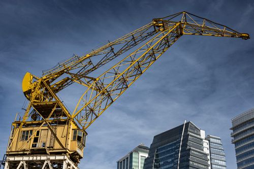Free Yellow construction crane against modern buildings in Buenos Aires, with a clear blue sky. Stock Photo