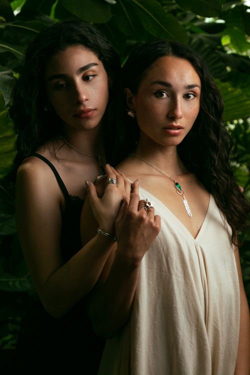 Free Artistic portrait of two women with jewelry in a lush green backdrop, exuding elegance. Stock Photo