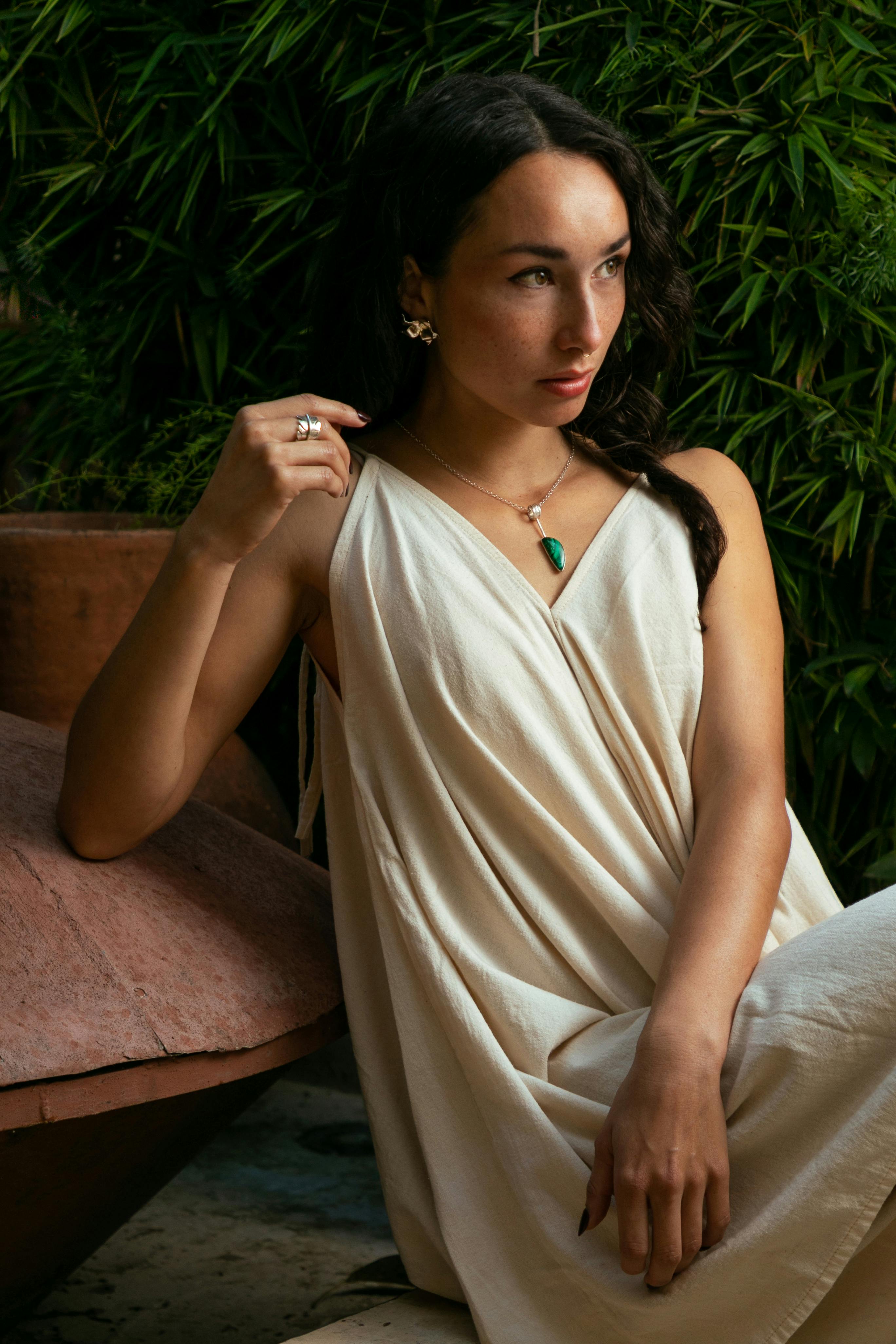 Elegant woman wearing jewelry, posing against lush greenery in San Cristóbal de las Casas, Mexico.