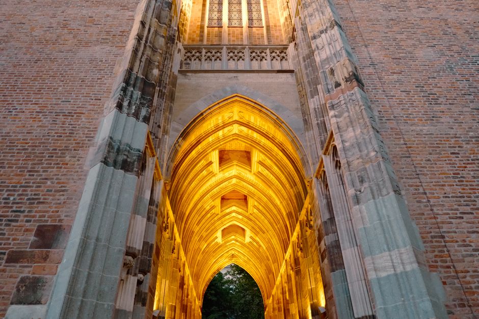 Illuminated Gothic archway with intricate brickwork in Utrecht, Netherlands.