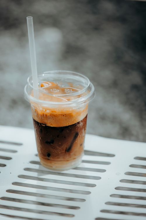 Free A refreshing iced coffee in a plastic cup with straw on a white table, perfect for a summer day. Stock Photo
