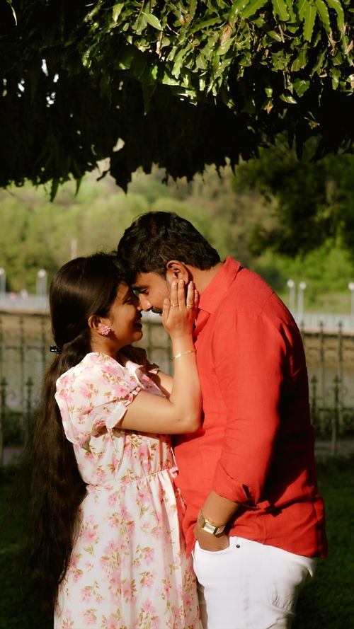 Free A loving couple shares a tender moment under leafy greenery in a serene park. Stock Photo