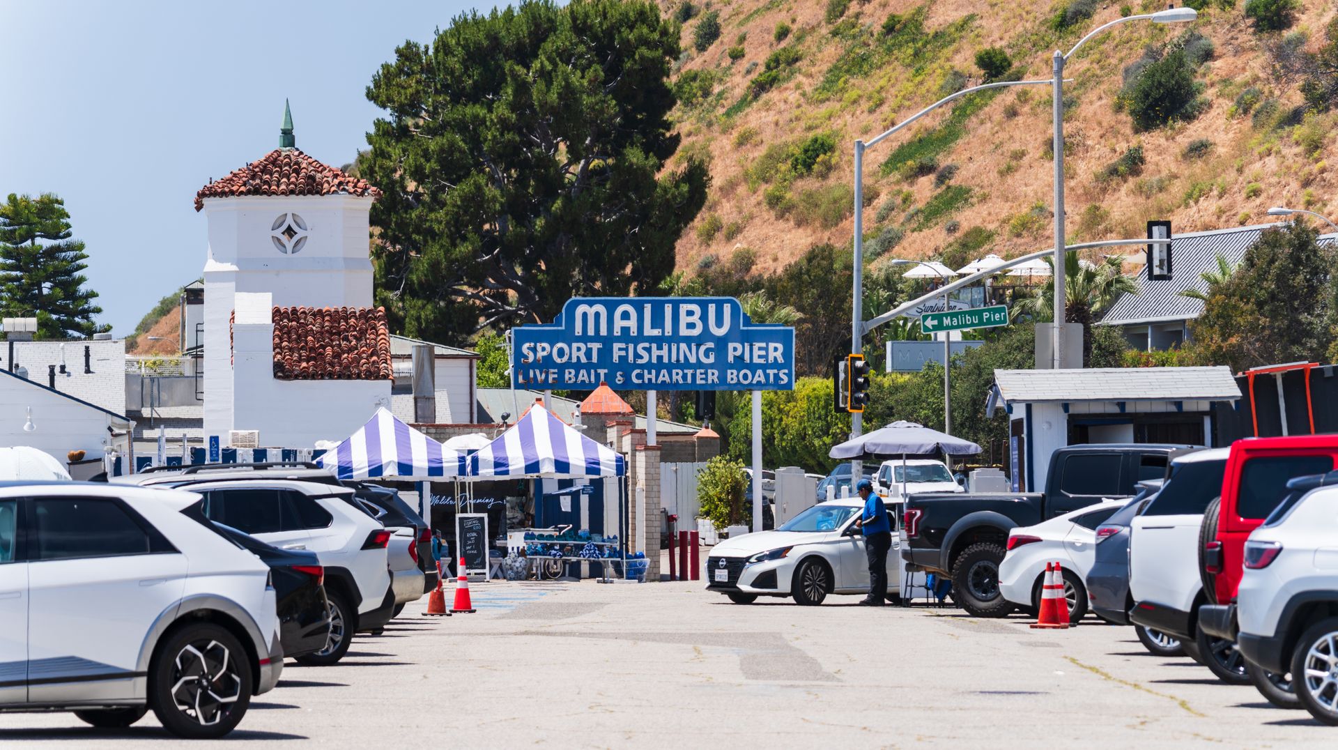 Lively view of Malibu Sport Fishing Pier entrance with parked cars and people.