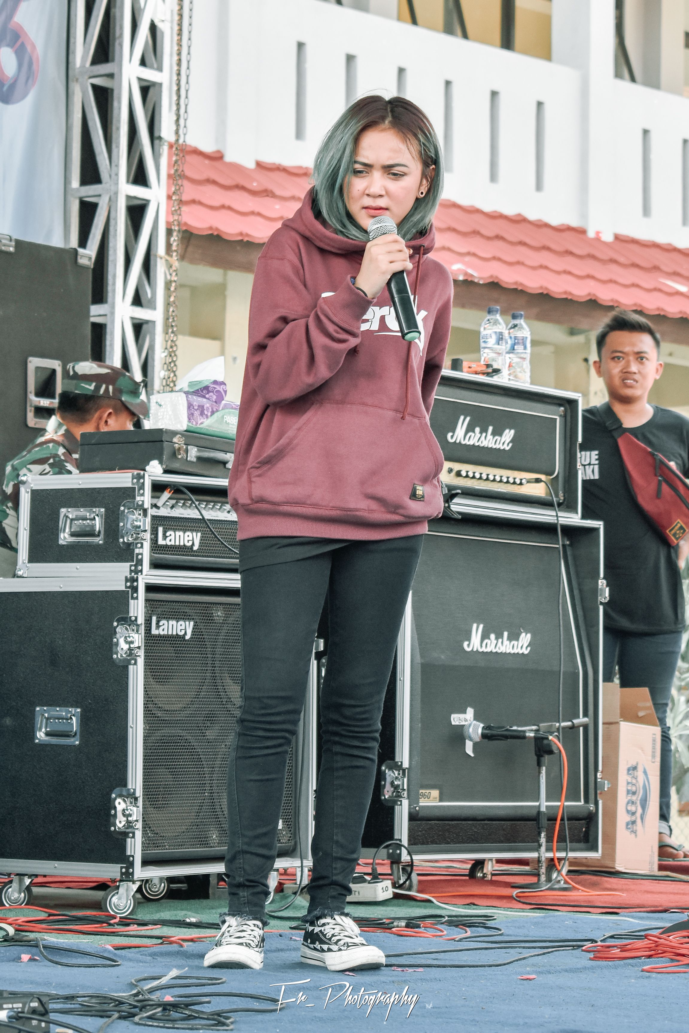 Female singer performing live at an outdoor concert with professional audio equipment.