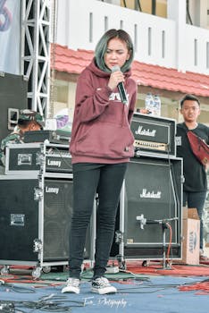 Female singer performing live at an outdoor concert with professional audio equipment.