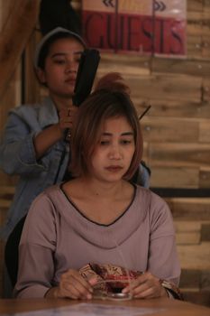 A woman is getting her hair styled in a cozy indoor salon setting.
