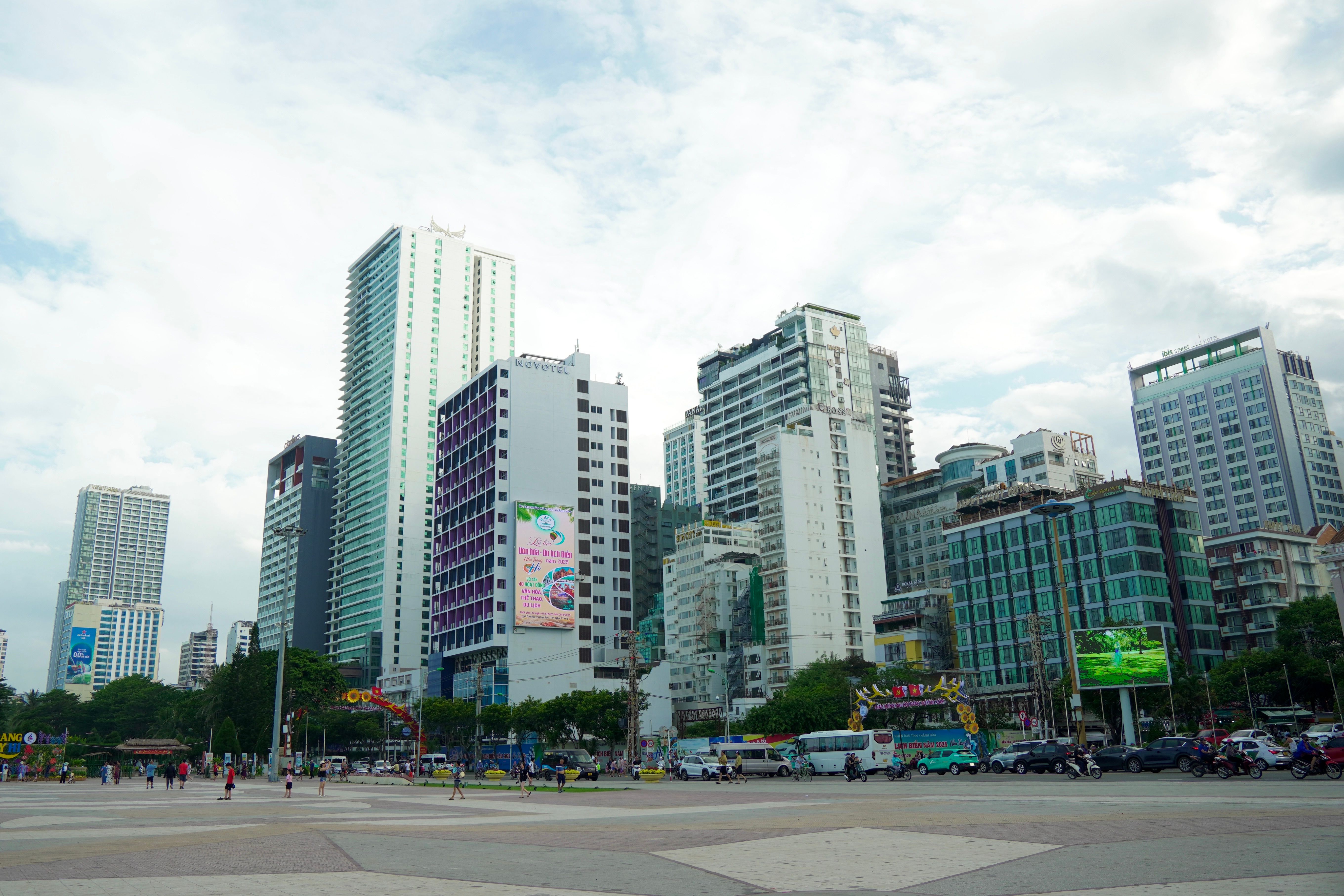 High-rise buildings in a bustling city center under a cloudy sky.