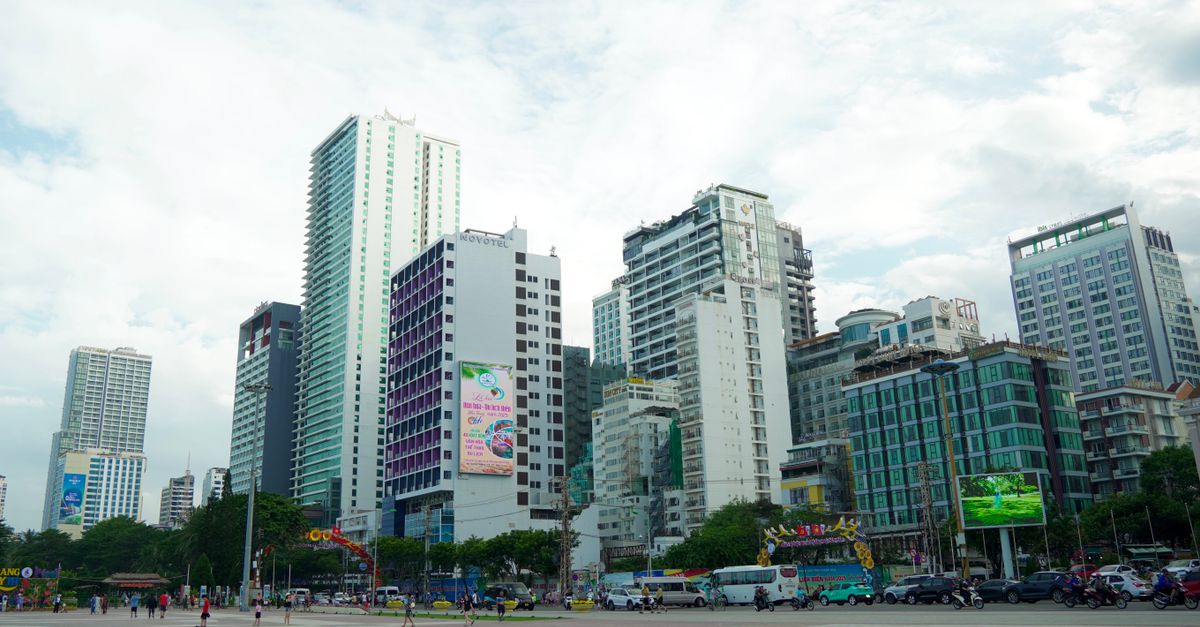 High-rise buildings in a bustling city center under a cloudy sky.