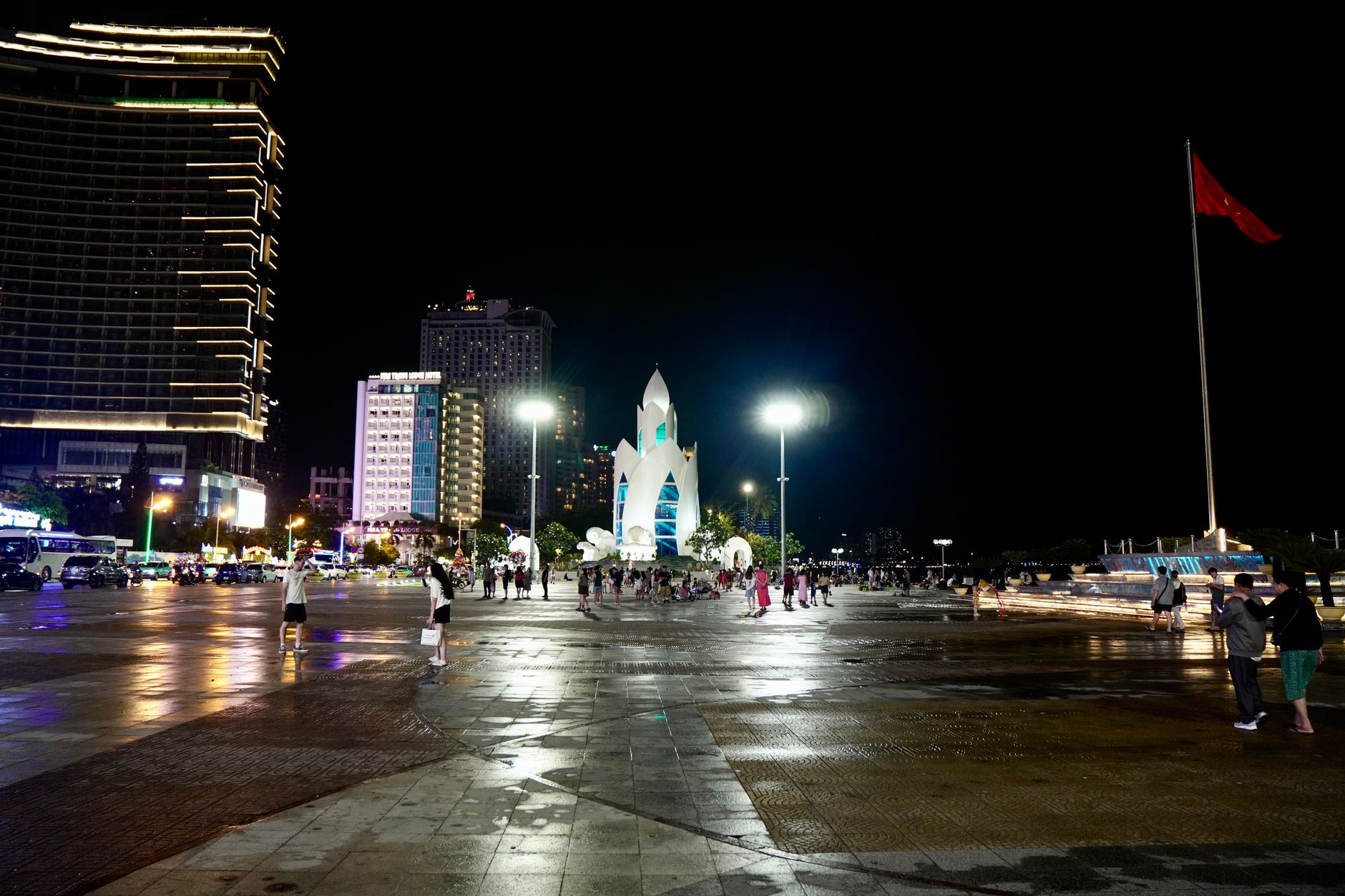 Illuminated Nha Trang cityscape at night featuring the iconic Lotus Tower and bustling square.