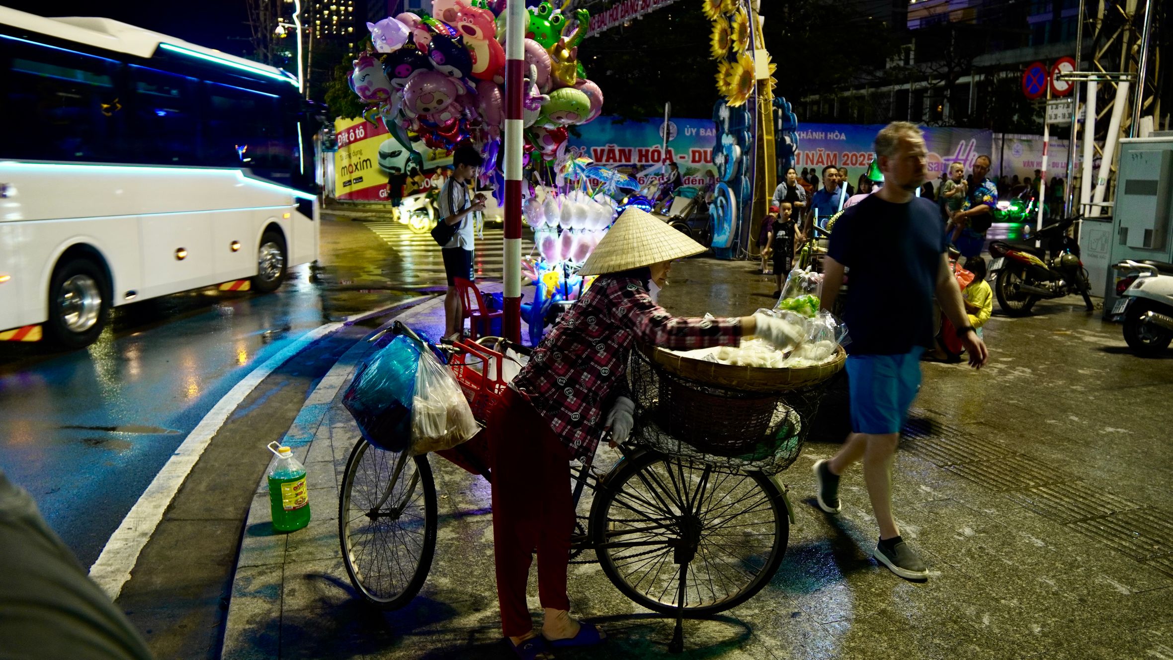 Vibrant night market scene with street vendor selling balloons on a bicycle cart.