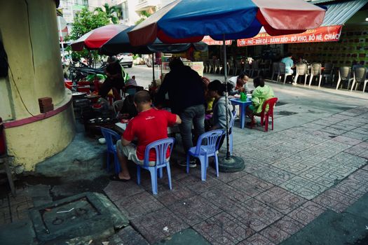 People enjoying street food under colorful umbrellas in a bustling urban setting.