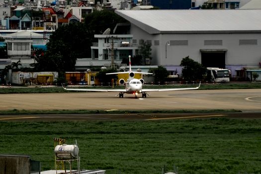 A private jet aligns on the runway amidst urban airport backdrops, ready for departure.
