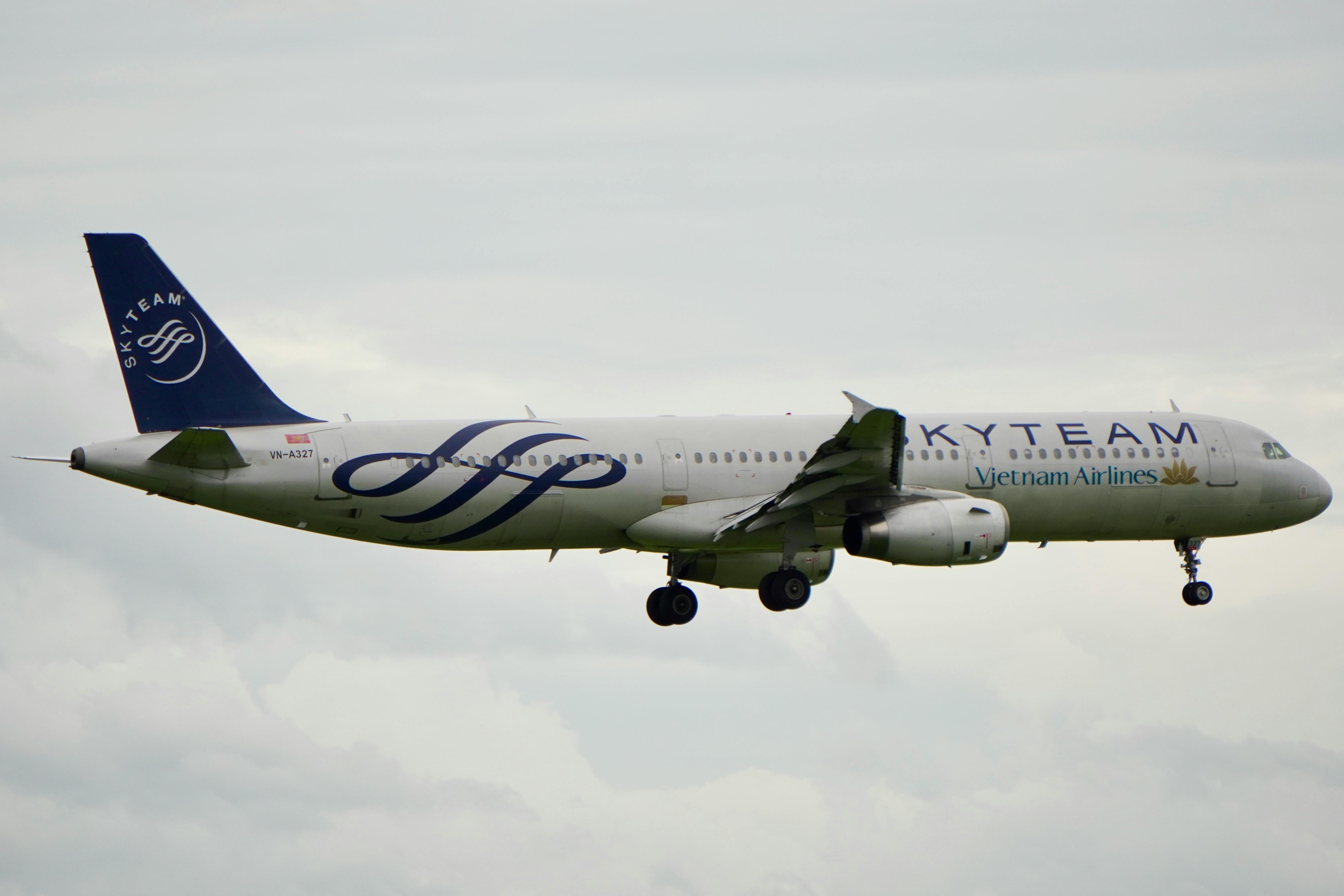 Vietnam Airlines plane with SkyTeam livery captured mid-flight against a cloudy sky.