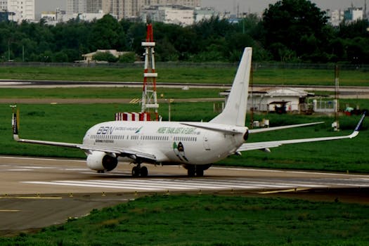 A commercial airplane taxiing on a runway with city skyline in the background.