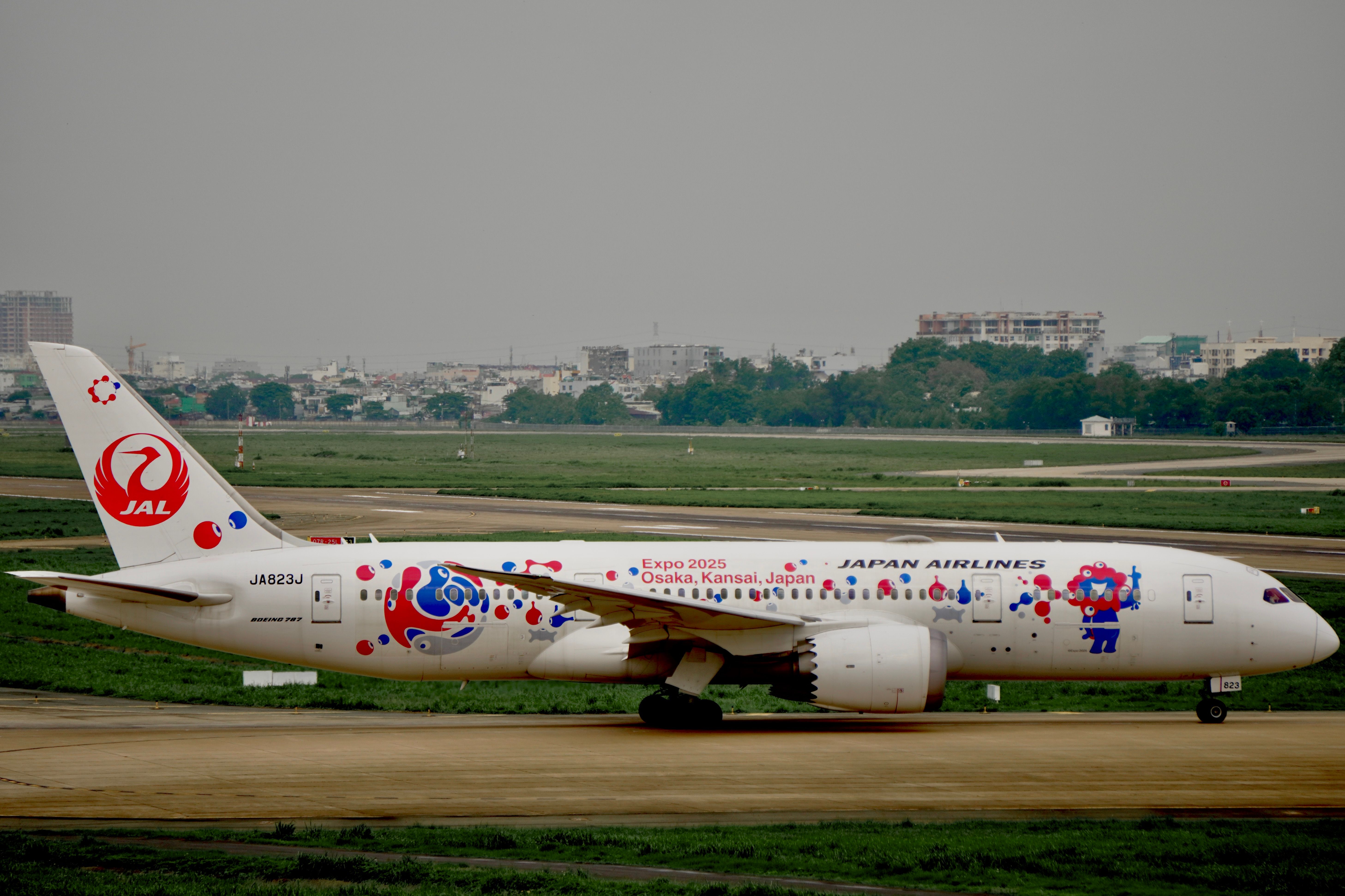 Japan Airlines Boeing 787 showcasing Expo 2025 Osaka livery during a daytime runway taxi.