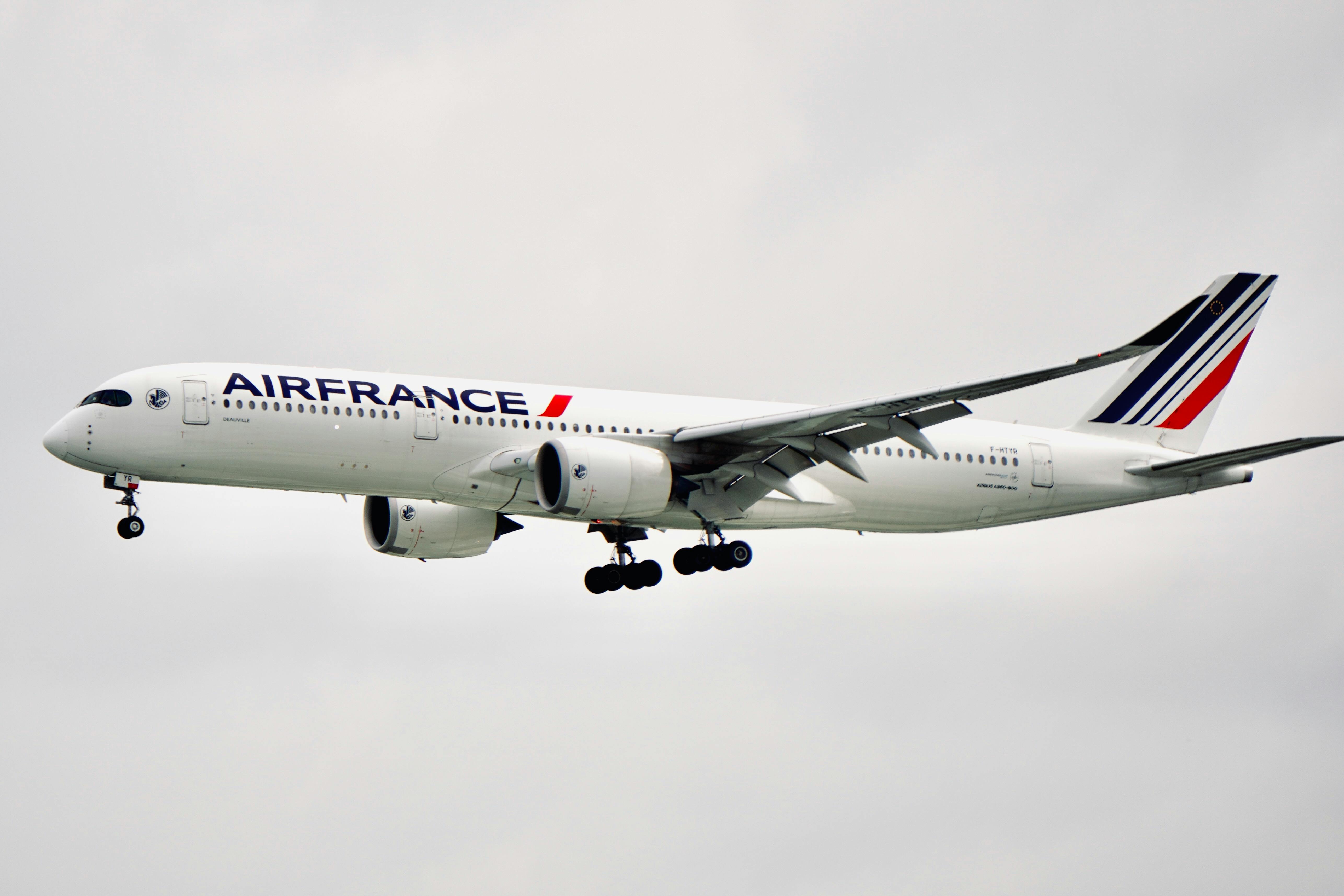 Free Air France Airbus A350 flying with landing gear extended against cloudy sky. Stock Photo