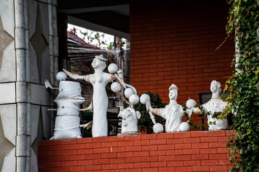 A collection of white sculptures on a red brick wall showcases artistic creativity outdoors.