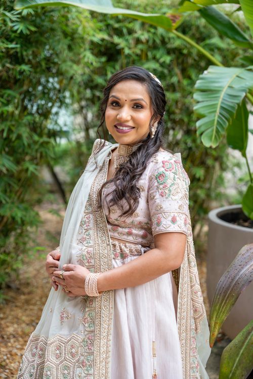 Free Pregnant woman in traditional attire standing in a lush garden, smiling warmly. Stock Photo