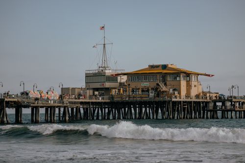 Free View of Santa Monica Pier with ocean waves and blue sky during the day. Stock Photo