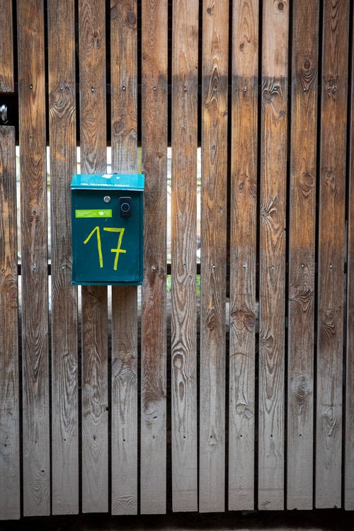 Free A green mailbox numbered 17 on a rustic wooden fence, creating a vintage outdoor feel. Stock Photo