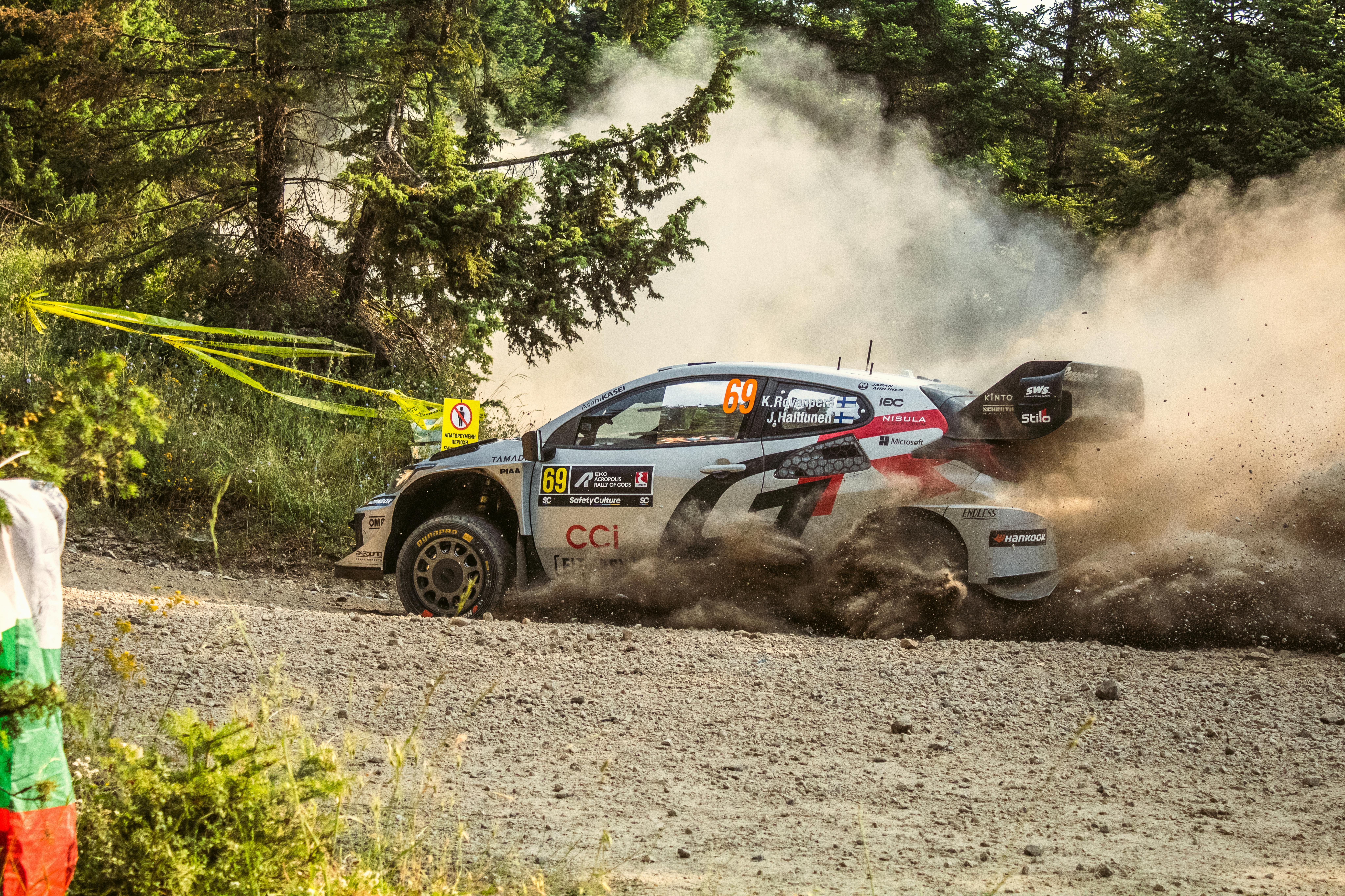 Dynamic rally car speeds through a dusty forest road in Pavliani, Greece.