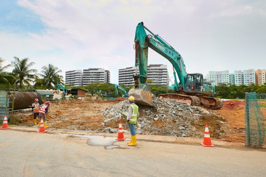 Urban construction site with workers and excavators under a clear sky.