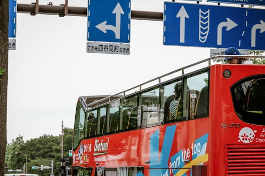 Tourists enjoy a sightseeing tour on an open-top bus in Shinjuku City, Tokyo, with visible road signs.
