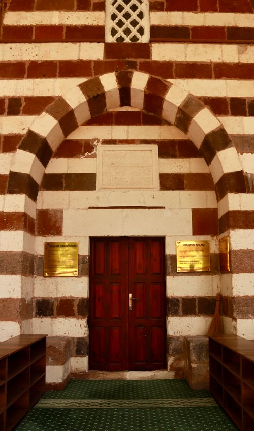 Free Elegant arched doorway with striped stonework, featuring a wooden door and traditional design. Stock Photo