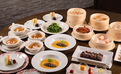 Free A lavish assortment of Asian dishes featuring dim sum, soups, and desserts beautifully arranged. Stock Photo