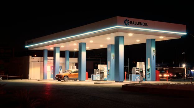 Brightly lit Ballenoil gas station in Málaga, captured during night with warm lighting.