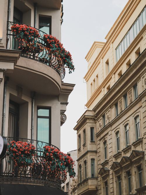 Free Picturesque balcony adorned with vibrant flowers on a historic European street. Stock Photo