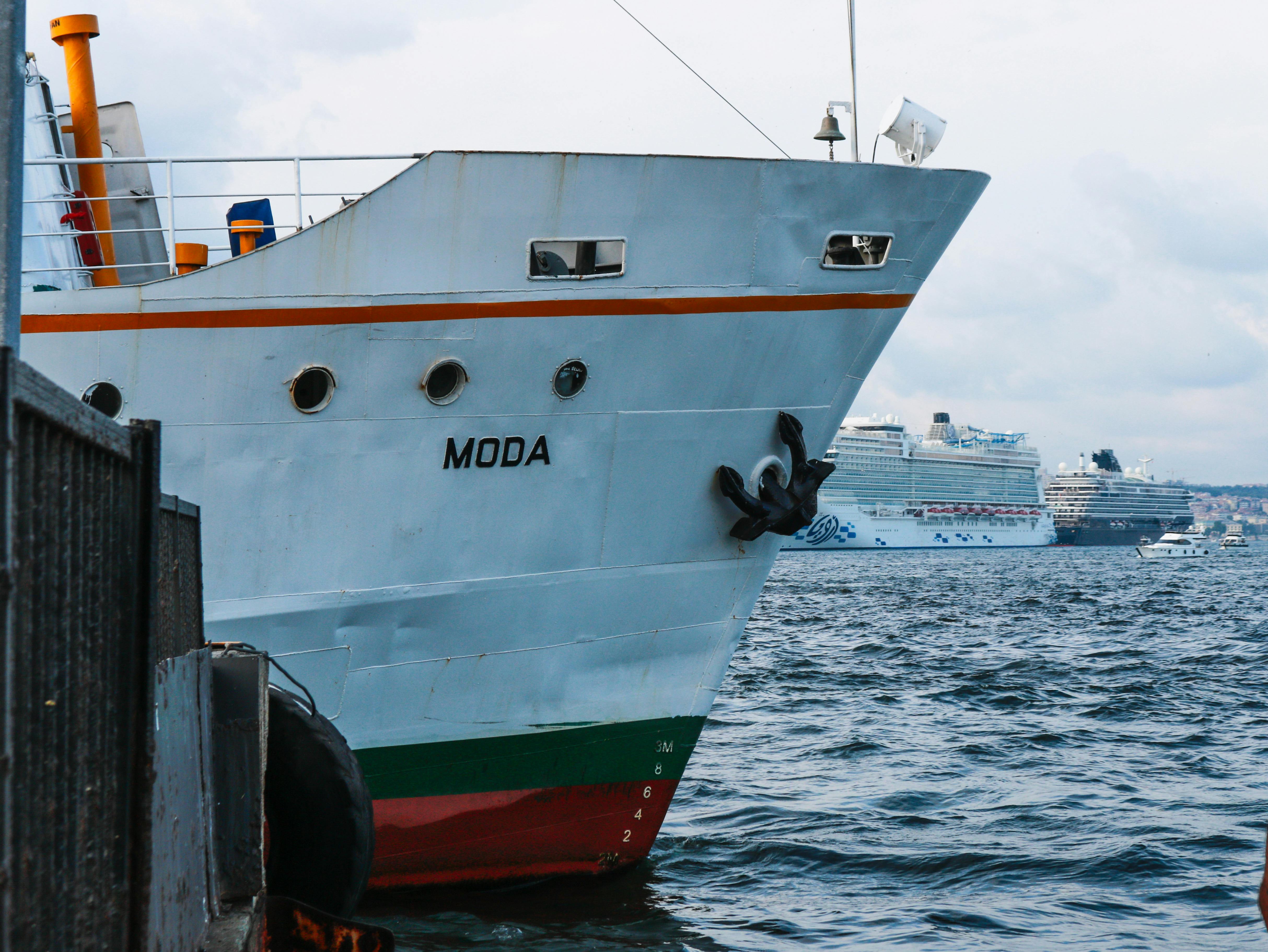 Gratis Primo piano della nave cargo 'MODA' attraccata in un porto trafficato, con navi da crociera sullo sfondo. Foto a disposizione
