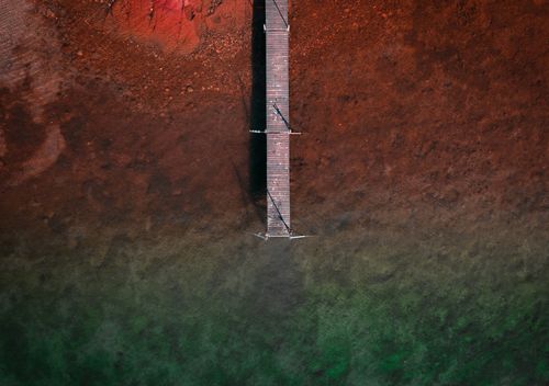 Free Stunning aerial shot of a wooden pier over colorful gradient water in Västernorrlands län, Sweden. Stock Photo