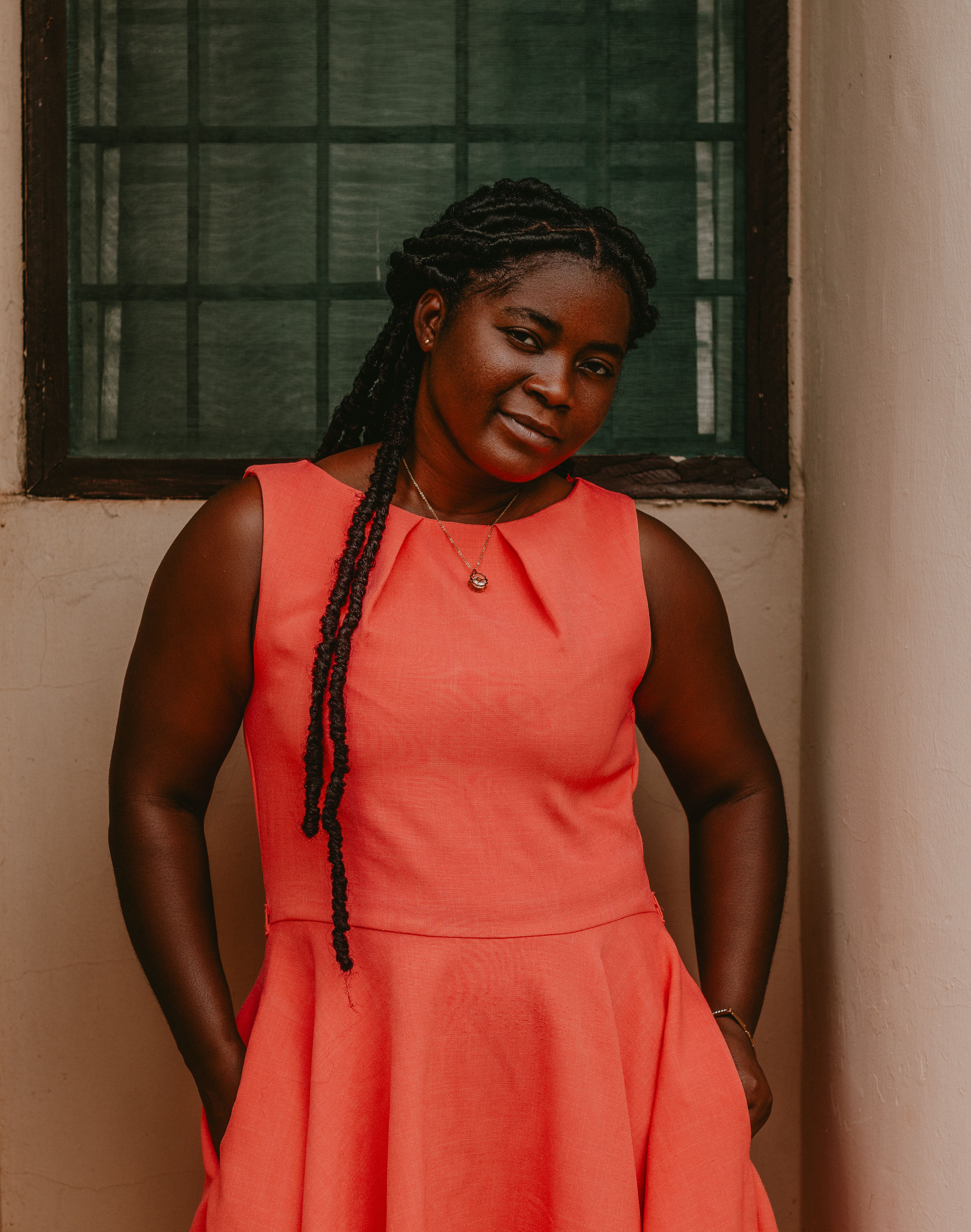 Stylish portrait of a woman in a bright red dress against a rustic background.