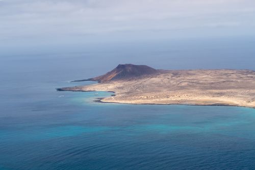 Free Stunning aerial photograph showcasing a volcanic island with a dramatic shoreline and expansive ocean view. Stock Photo