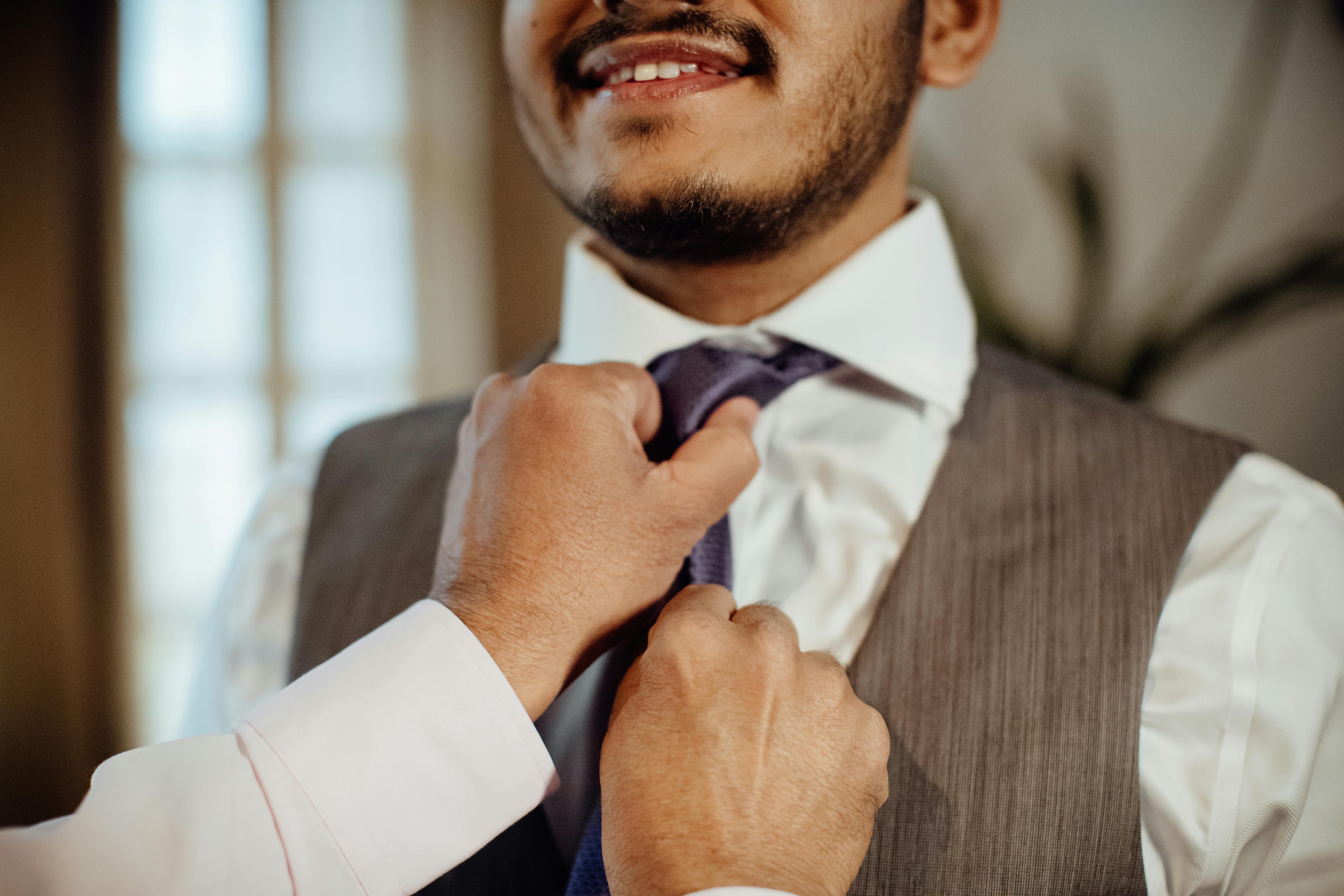 Zadarmo Detailný záber muža, ktorý si v interiéri upravuje kravatu a pripravuje sa na formálnu udalosť. Fotka z fotobanky