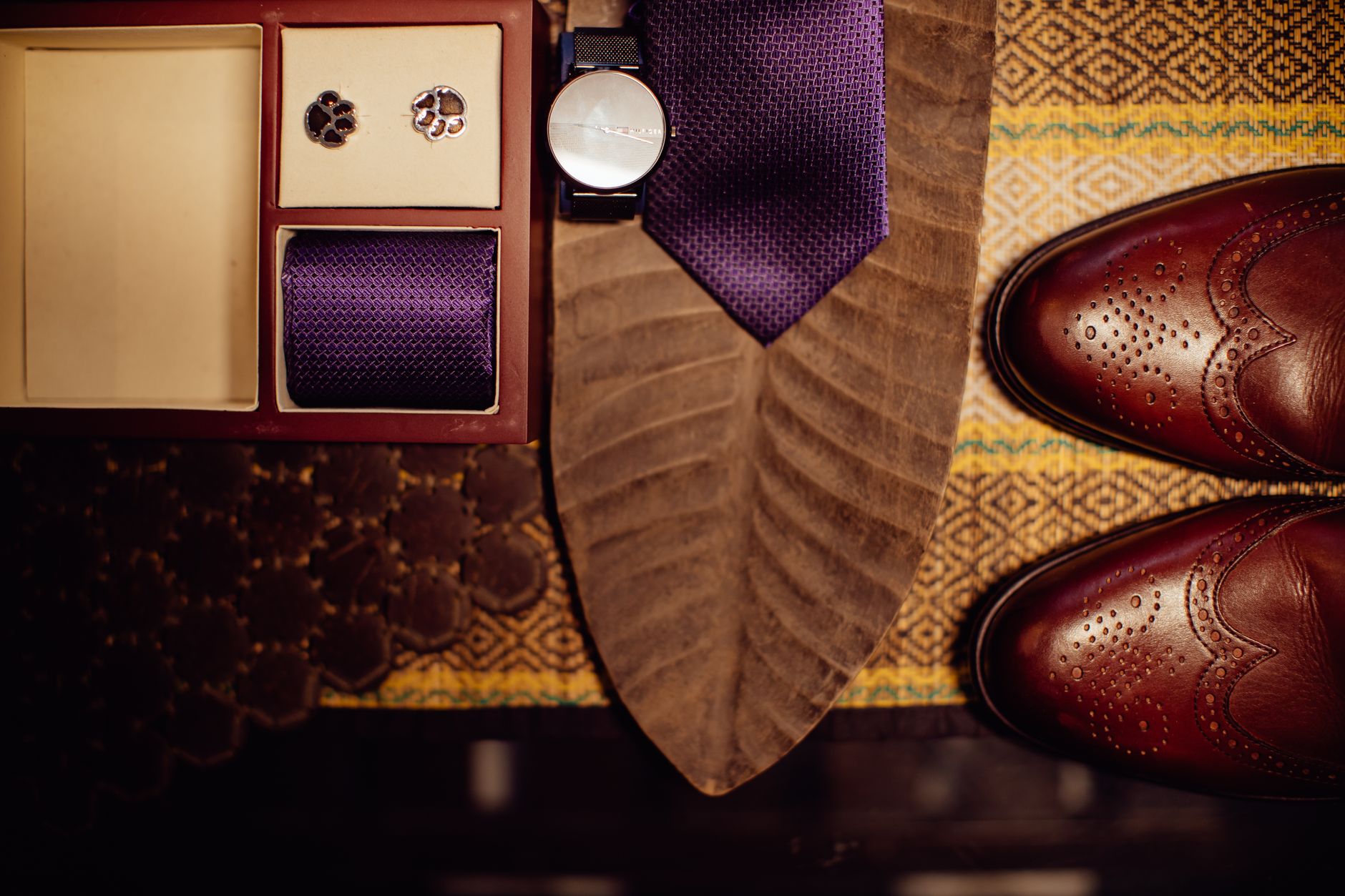 How To Build A Capsule Wardrobe With 20 Classic Pieces 1 Flat lay of men's accessories featuring a purple tie, cufflinks, watch, and leather shoes.