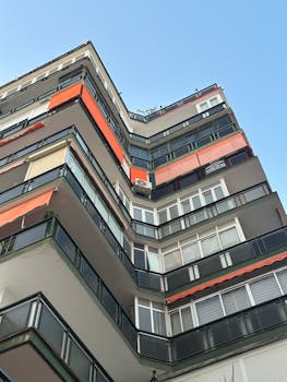 High-rise apartment building with vibrant orange awnings under clear blue sky.