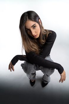 A stylish young woman with long hair posing confidently in a modern, urban outfit.